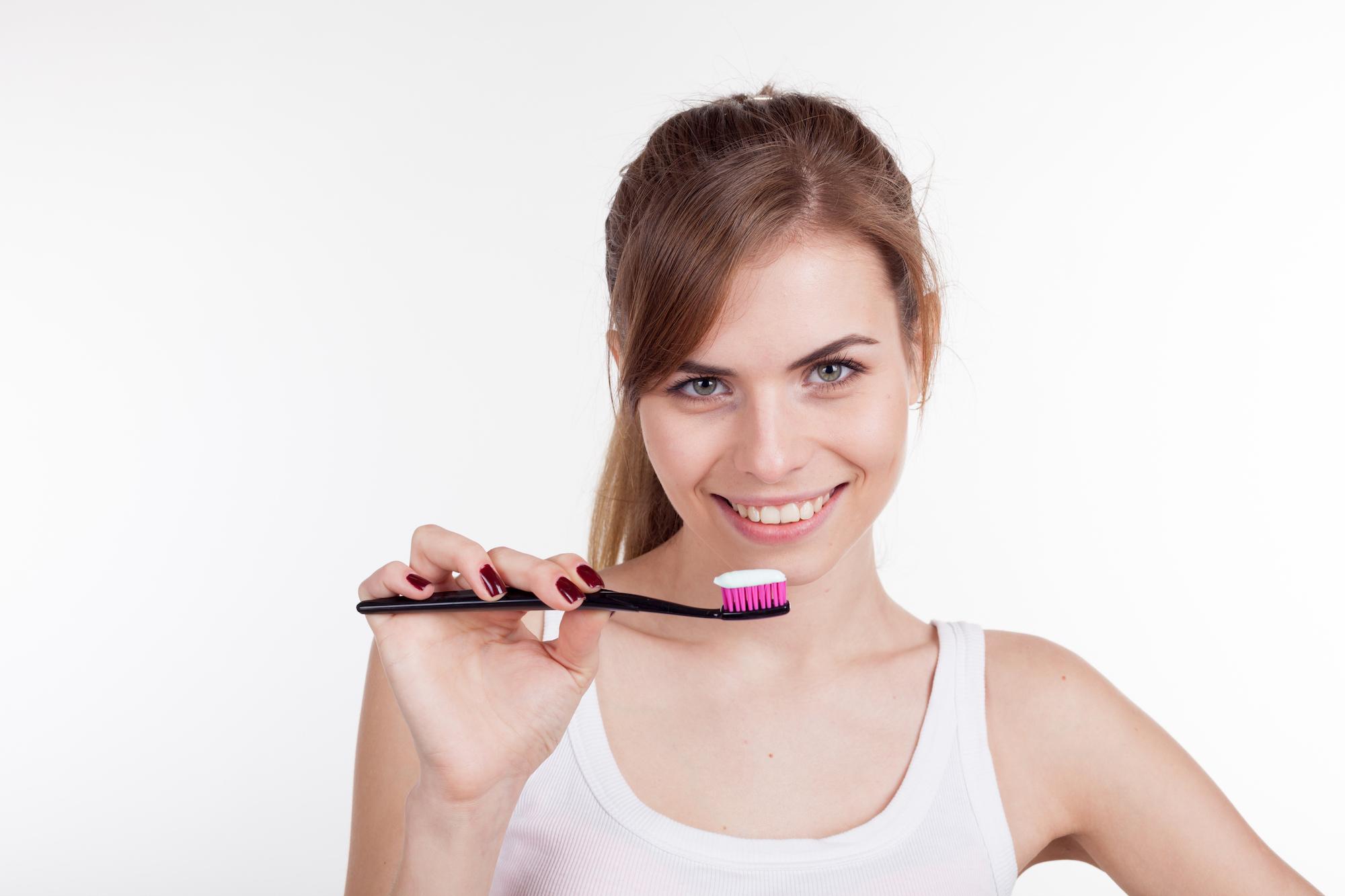 girl holding a toothbrush smiles igiene dentale pulizia dei denti